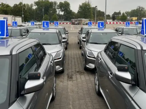 Rząd srebrnych aut z niebieskimi literami "L" na dachach. Czekają na kursantów, którzy zdali teorię i chcą jak najszybciej zdać praktykę.