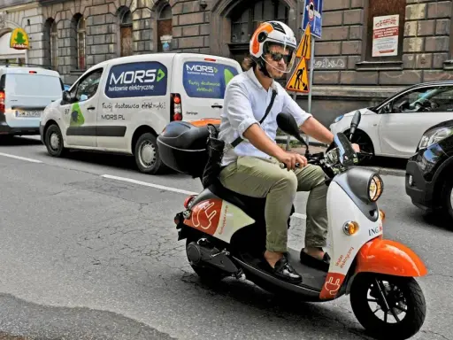 Mężczyzna w kasku jedzie skuterem elektrycznym, przygotowując się do testu na kartę motorowerową.