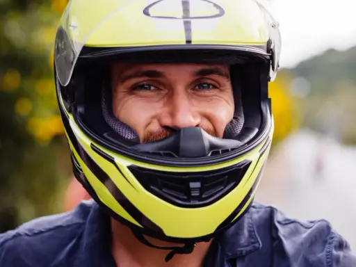Uśmiechnięty mężczyzna w żółtym kasku motocyklowym. Dobór odpowiednich rozmiarów kasków motocyklowych to klucz do bezpieczeństwa.