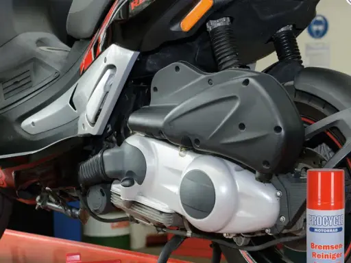 Skuter Gilera z widocznym elementem napędowym. Puszka środka do czyszczenia hamulców obok sugeruje problemy, być może związane z zużytym wariatorem w skuterze objawy.