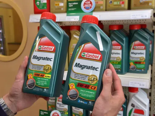 Ręce trzymają butelki oleju silnikowego Castrol Magnatec. Czy Castrol to dobry olej? Ten produkt zapewnia natychmiastową ochronę silnika.