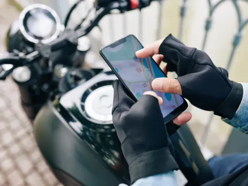 Motocyklista w rękawiczkach sprawdza trasę na mapie w aplikacji dla motocyklistów.