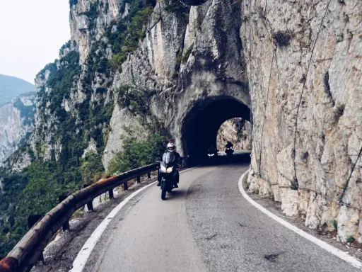 Motocykliści przemierzają malowniczą strada della forra, wjeżdżając w skalny tunel. Widok na jezioro i góry zapiera dech.