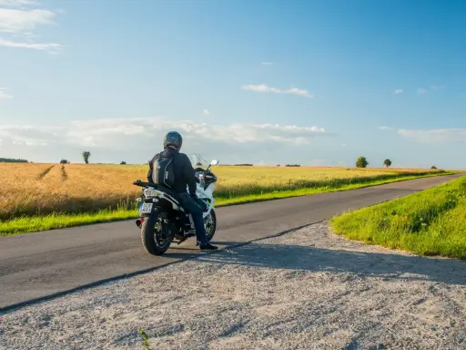 Motocyklista na tle pól pszenicy, odkrywa malownicze trasy motocyklowe mazowieckie.