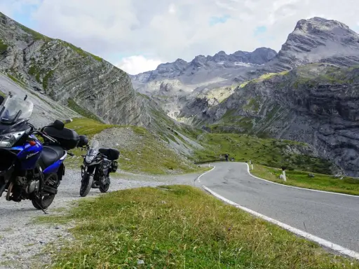 Dwa motocykle czekają na przygodę na krętej drodze przez alpejskie krajobrazy. Idealne trasy motocyklowe Austria!
