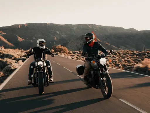 Dwóch motocyklistów w stylowym ubraniu na motor turystyczny przemierza pustynną drogę.