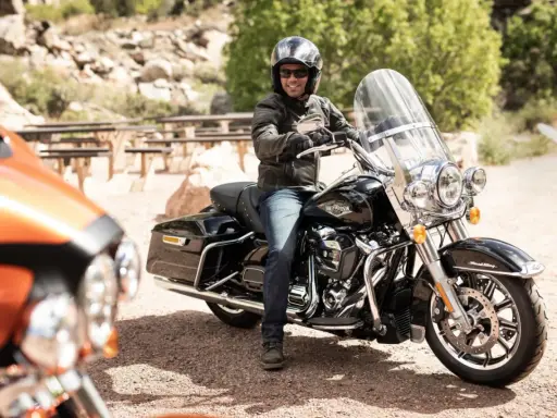 Mężczyzna na czarnym motocyklu Harley-Davidson, wyposażonym w gmole, gotowy na podróż.