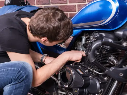 Mężczyzna naprawia niebieski motocykl. Czy to CBS?