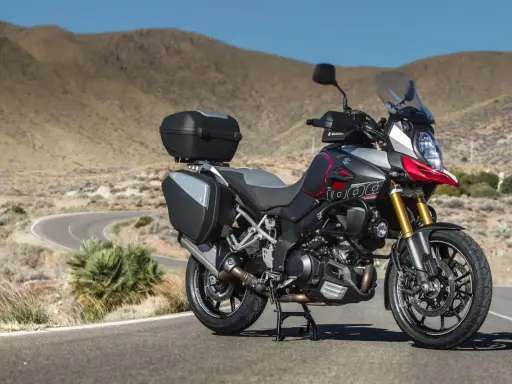 Suzuki DL 1000 V-Strom z kuframi, gotowy na przygodę na krętej drodze pośród pustynnych wzgórz.