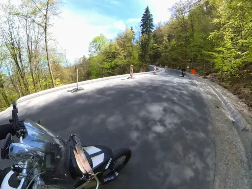 Motocyklista pokonuje zakręty najbardziej krętej drogi w Polsce, otoczonej bujną zielenią lasu.