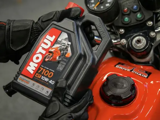 Rękawice motocyklowe trzymają olej Motul 7100 10W-40. Sprawdź, co ile wymieniać olej w motocyklu, by zapewnić mu długą żywotność.