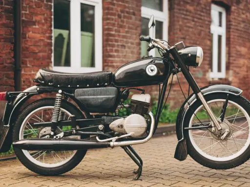 Czarny motocykl wsk 125 na tle ceglanego budynku. Klasyk z PRL-u gotowy do jazdy.