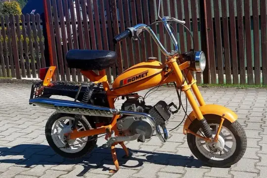 Pomarańczowy Romet, jeden z klasycznych nowych polskich motocykli, gotowy do jazdy po bruku.
