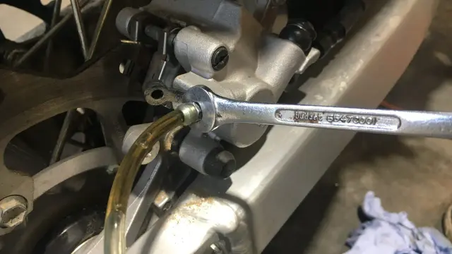 Klucz nasadowy odkręca odpowietrznik zacisku hamulcowego motocykla, co jest częścią procesu wymiany płynu hamulcowego.