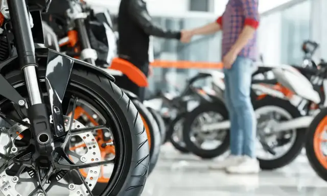 Dwóch mężczyzn ściska sobie dłonie przy motocyklach. Sfinalizowali sprzedaż motocykla przed upływem 6 miesięcy.