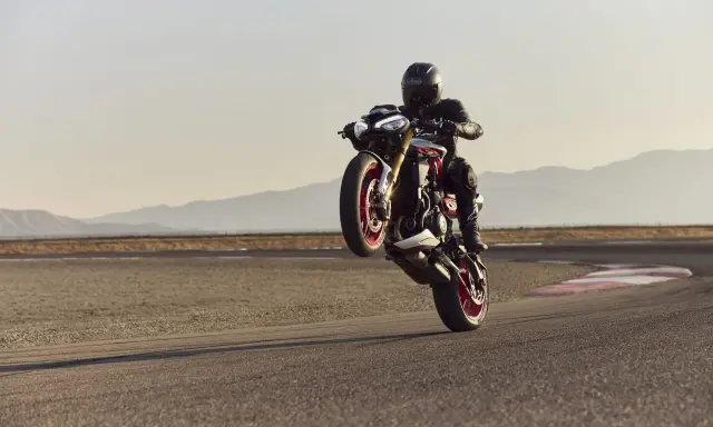 Motocyklista na torze wykonuje wheelie. System kontroli trakcji co to? Pomaga utrzymać przyczepność podczas takich manewrów.