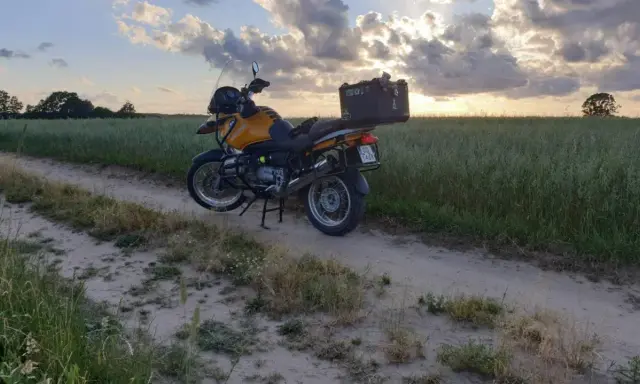 Żółty motocykl turystyczny na piaszczystej drodze wśród pól. Idealne miejsce na odkrywanie tras motocyklowych Kaszuby.