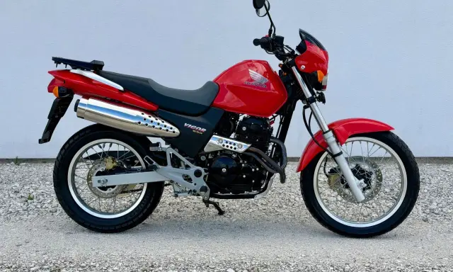 Czerwony Honda Dominator 650 Vigor. Wady i zalety tego motocykla to m.in. jego wszechstronność i prostota konstrukcji.