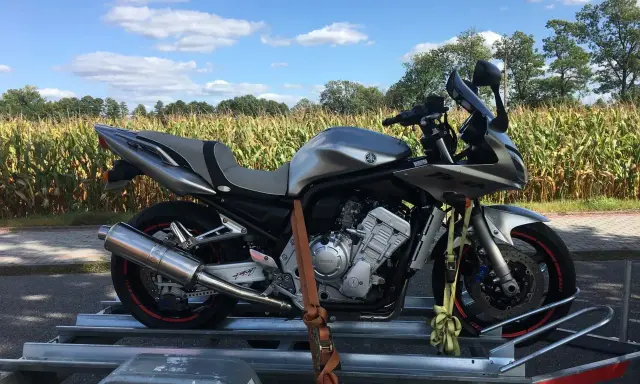 Srebrny motocykl na przyczepce, gotowy do transportu. Może to być związane z akcyzą na motocykle, która wpływa na koszty zakupu.