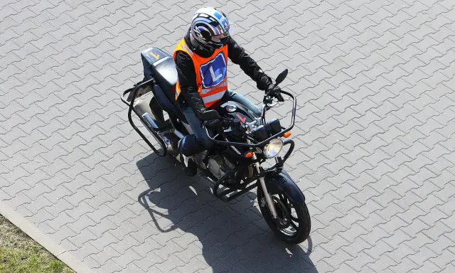 Osoba w kamizelce z literą "L" na motocyklu, przygotowuje się do egzaminu na prawo jazdy kategorii A2. Od ilu lat można zdawać?
