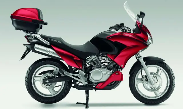Czerwony motocykl Honda Varadero 125 z kufrem, gotowy na odblokowanie mocy i przygodę.