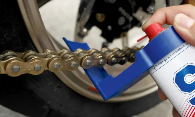 Czyszczenie i smarowanie łańcucha motocyklowego. Specjalny aplikator ułatwia dotarcie do wszystkich ogniw, pomagając w utrzymaniu napędu w idealnym stanie.