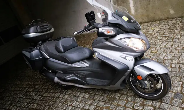Srebrny Suzuki Burgman 650 z kuframi, gotowy do podróży. Czy są jakieś wady?