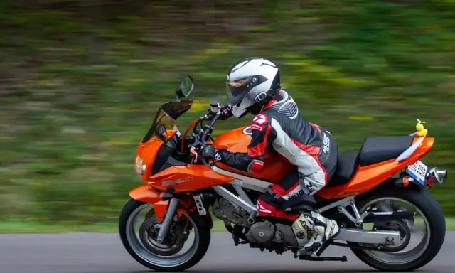 Motocyklista w kombinezonie śmiga pomarańczowym motocyklem. Idealna trasa motocyklowa Śląsk na weekendową przejażdżkę.