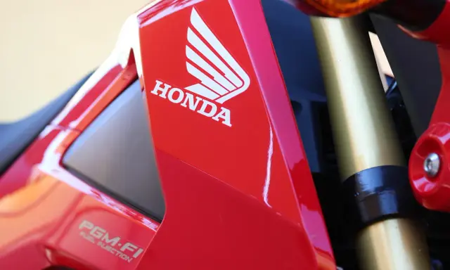 Czerwony motocykl Honda z logo i napisem PGM-FI. Pamiętaj o regularnych przeglądach motocykla 125!