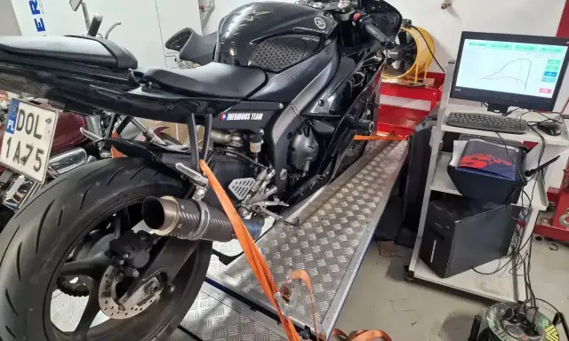 Czarny motocykl na hamowni, przygotowany do **blokowania motocykla na A2**. Pomiar mocy i momentu obrotowego.