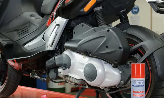 Skuter Gilera z widocznym elementem napędowym. Puszka środka do czyszczenia hamulców obok sugeruje problemy, być może związane z zużytym wariatorem w skuterze objawy.
