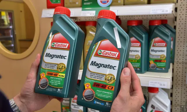 Ręce trzymają butelki oleju silnikowego Castrol Magnatec. Czy Castrol to dobry olej? Ten produkt zapewnia natychmiastową ochronę silnika.