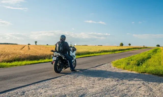 Motocyklista na tle pól pszenicy, odkrywa malownicze trasy motocyklowe mazowieckie.