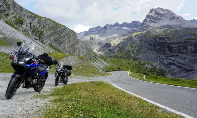 Dwa motocykle czekają na przygodę na krętej drodze przez alpejskie krajobrazy. Idealne trasy motocyklowe Austria!