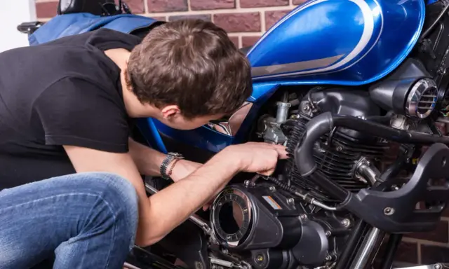 Mężczyzna naprawia niebieski motocykl. Czy to CBS?