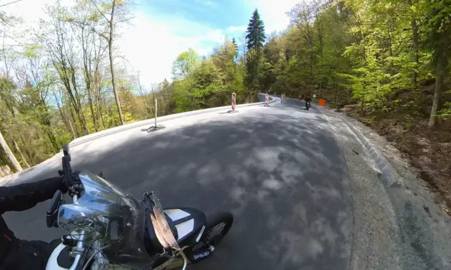 Motocyklista pokonuje zakręty najbardziej krętej drogi w Polsce, otoczonej bujną zielenią lasu.