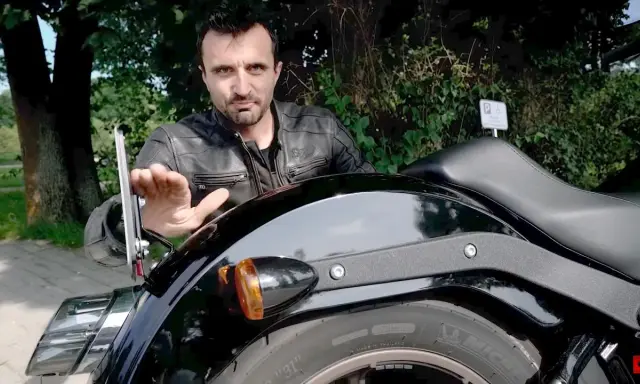 Mężczyzna pokazuje mocowanie tablicy rejestracyjnej motocykl, omawiając przepisy.
