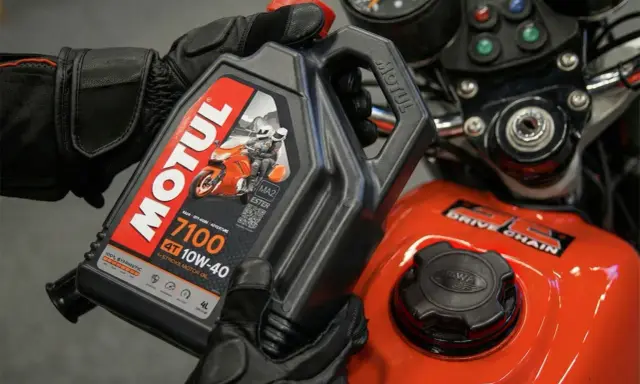 Rękawice motocyklowe trzymają olej Motul 7100 10W-40. Sprawdź, co ile wymieniać olej w motocyklu, by zapewnić mu długą żywotność.