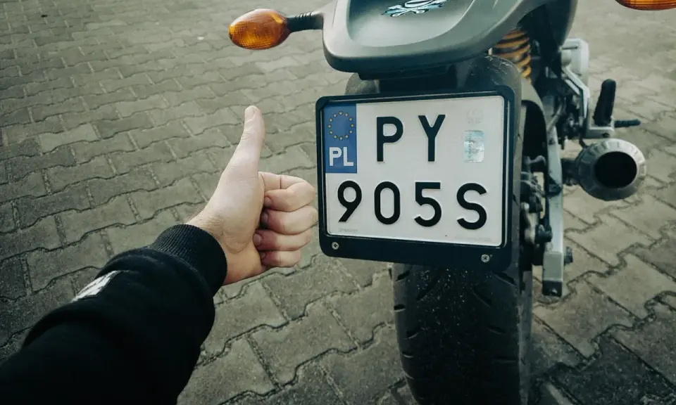 Kciuk w górę przy rejestracji starego motocykla z dokumentami. PY 905S.