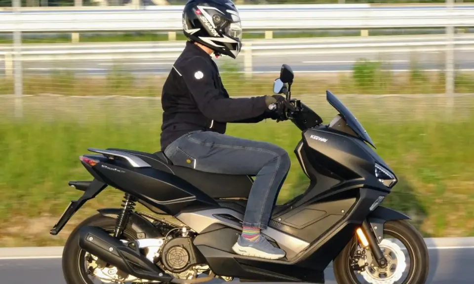 Mężczyzna w kasku i jeansach odbywa ekscytującą jazdę na skuterze Keeway.