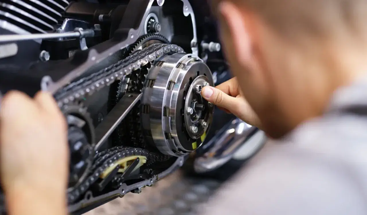 Mechanik pracuje nad mechanizmem motocykla, który umożliwia zmianę biegów bez sprzęgła.