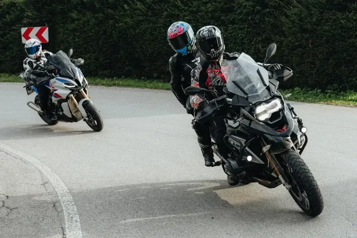 Motocykliści na zakręcie, jeden z pasażerem. Płynna zmiana biegów bez sprzęgła to klucz do dynamicznej jazdy.