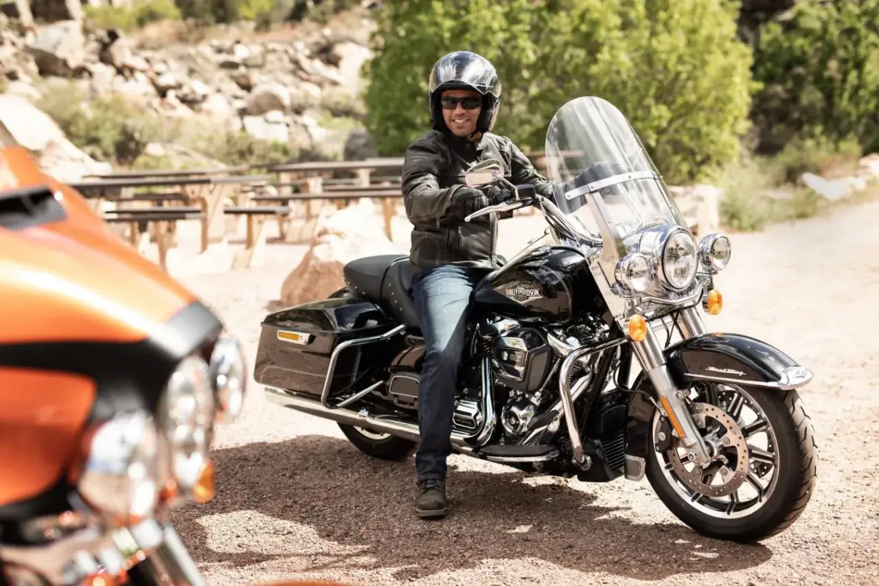 Mężczyzna na czarnym motocyklu Harley-Davidson, wyposażonym w gmole, gotowy na podróż.