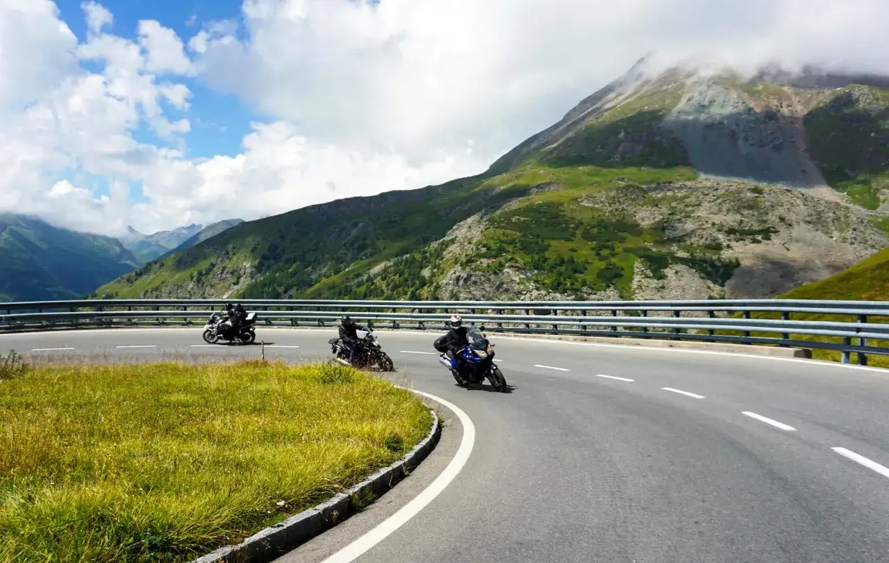 Motocykliści przemierzają malownicze trasy motocyklowe w Austrii, pokonując zakręty górskiej drogi na tle spektakularnych krajobrazów.