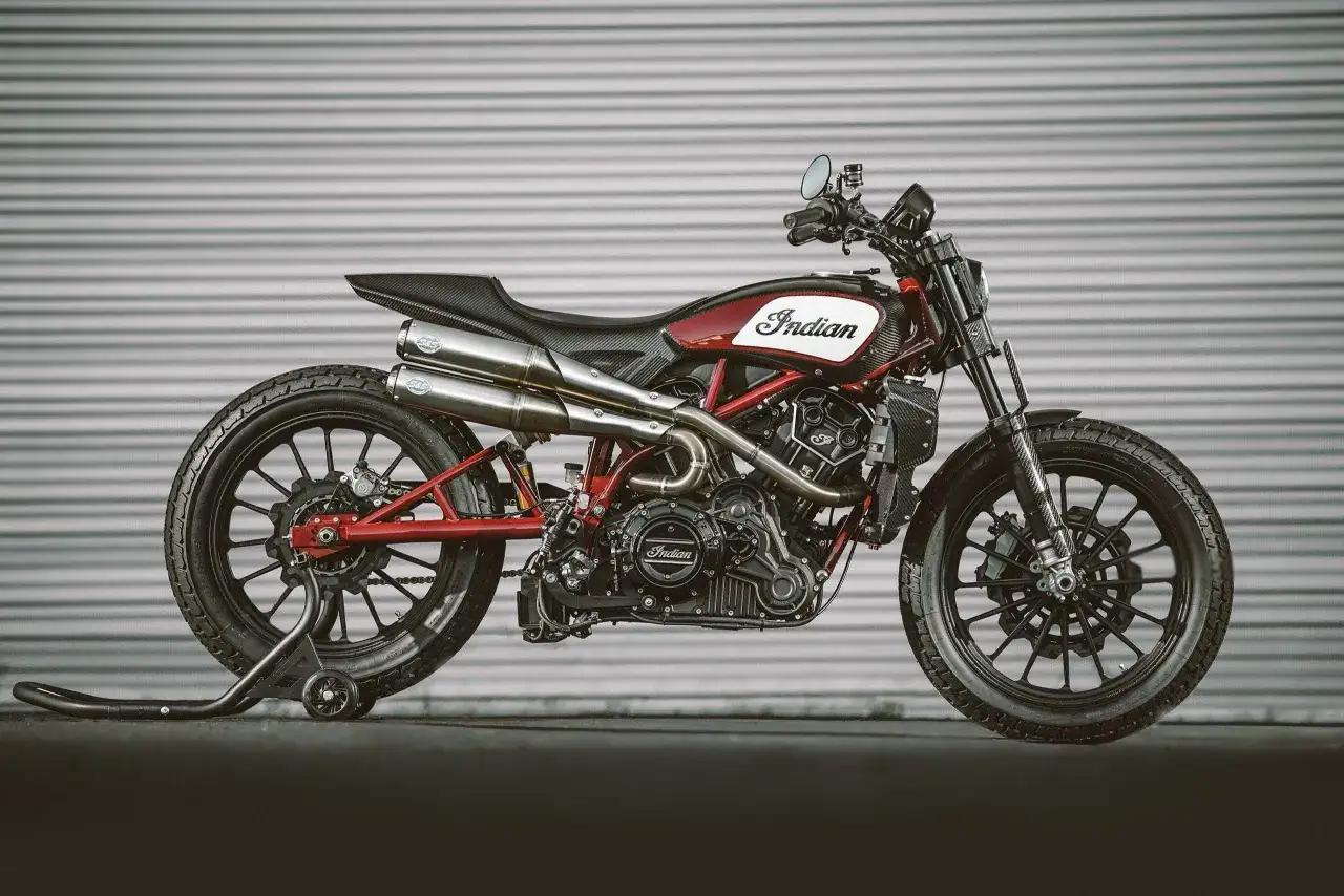 Stylowy motocykl Indian FTR 1200 w kolorze czerwono-białym, z elementami z włókna węglowego i podwójnym wydechem.