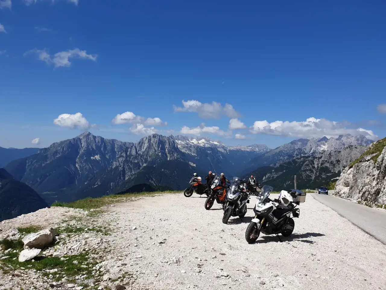 Grupa motocyklistów odpoczywa na tle majestatycznych gór, ciesząc się pięknymi trasami motocyklowymi w Austrii.