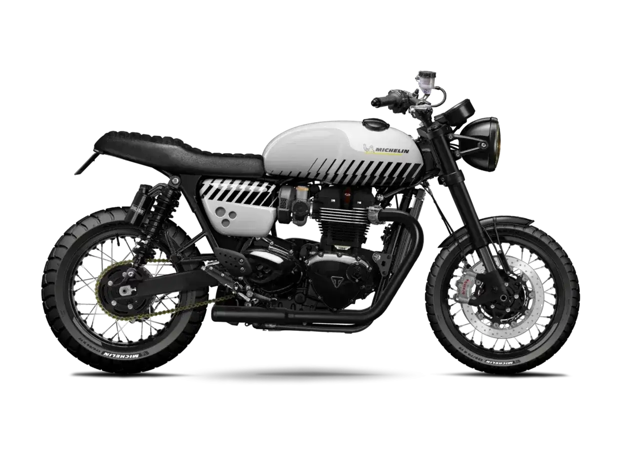 Stylowy Triumph Thruxton 900 w białym malowaniu z czarnymi błyskawicami i logo Michelin. Gotowy na triumfalną jazdę.