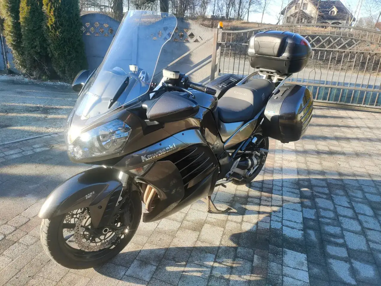 Ciemnobrązowy motocykl Kawasaki GTR 1000 z kuframi i dużą szybą, gotowy na dalekie podróże.