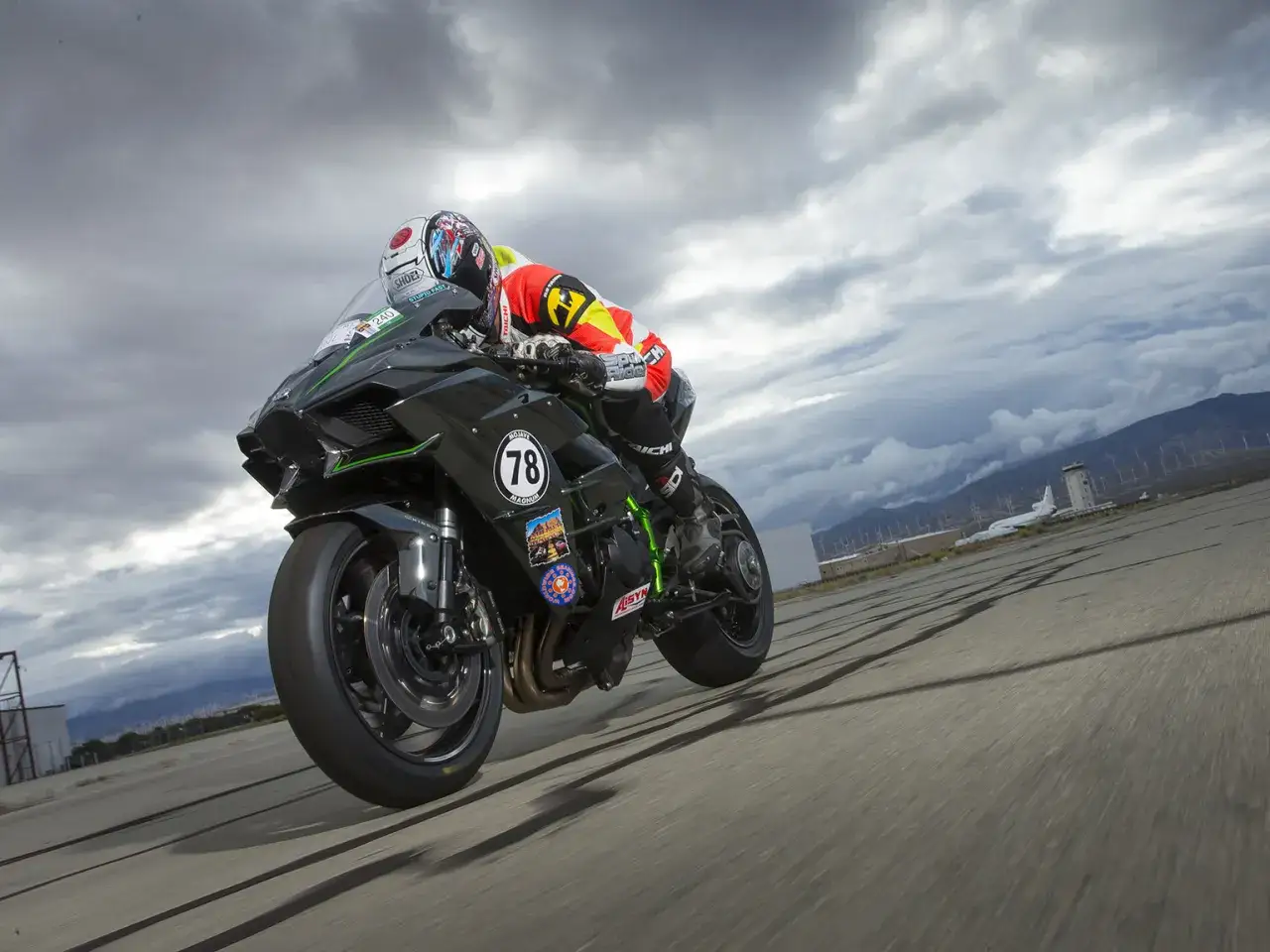Motocyklista na Kawasaki H2R w pełnym stroju, pochylony na zakręcie, gotowy do przyspieszenia 0-100.