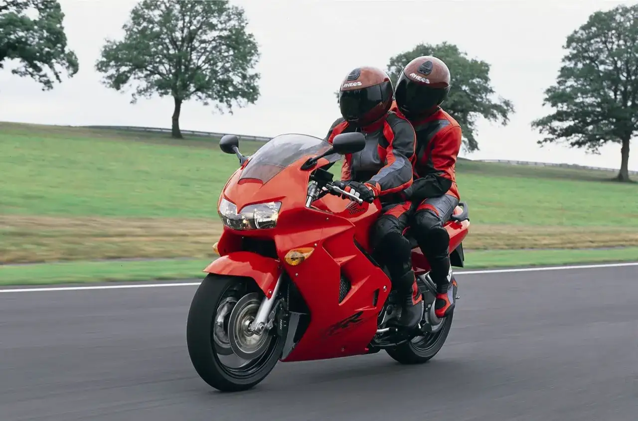 Czerwona Honda VFR 800 z dwoma motocyklistami w kombinezonach. Choć piękna, ma swoje wady.